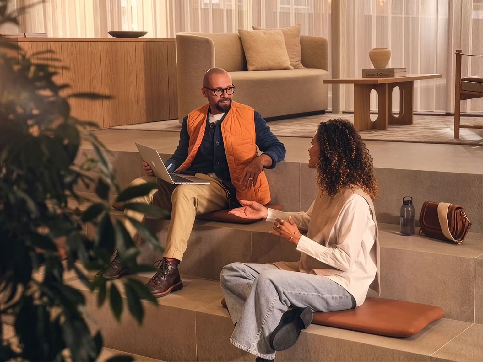 Two people in unhurried conversation in a warm, light-filled space.